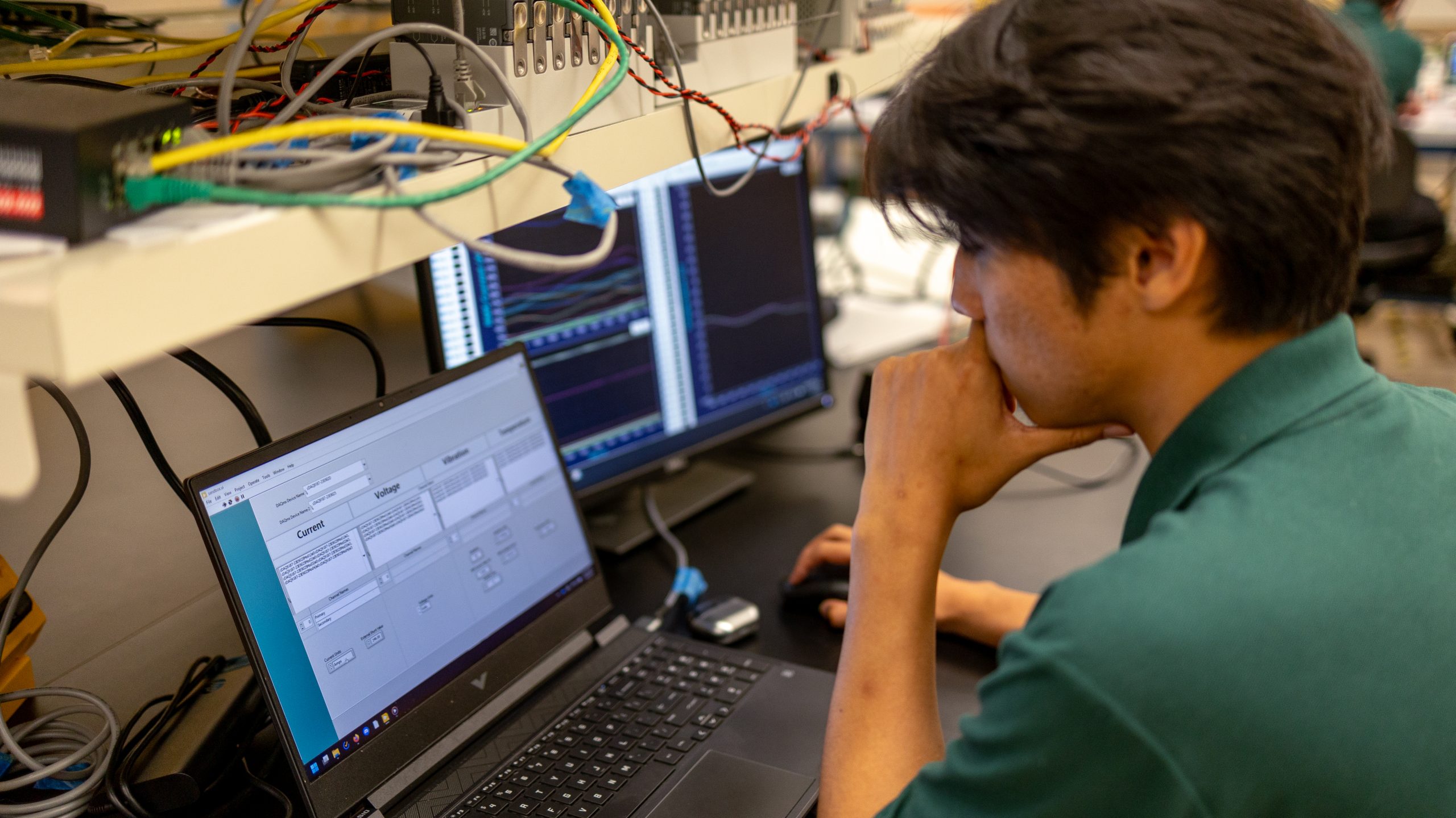 student looking at laptop screen surrounded by test equipment